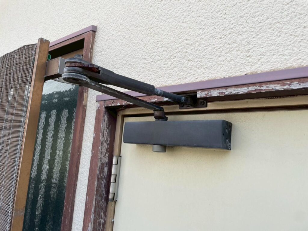 ドア上部の蝶番には錆が発生しており、このまま放置すると破損の恐れがあります。錆落としと下地処理を施した上で塗装し、金物の耐久性を回復させます。