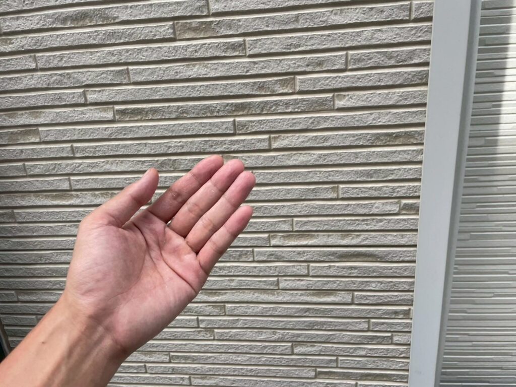 手に粉は付着していませんが、外壁表面には黒ズミが見られ、塗膜の保護機能が低下し始めているサインが確認できます。