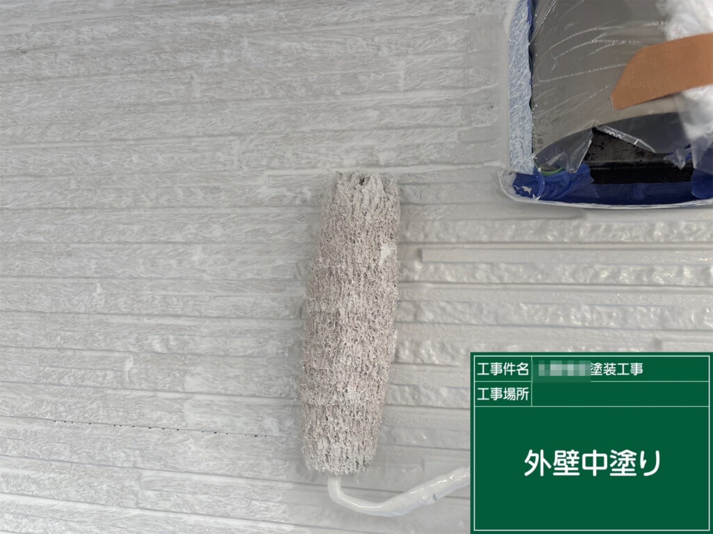 外壁の中塗りを「パールグレー」で施工します。ローラーで凹凸に塗料を押し込み、塗り残しが出ないように丁寧に塗布します。