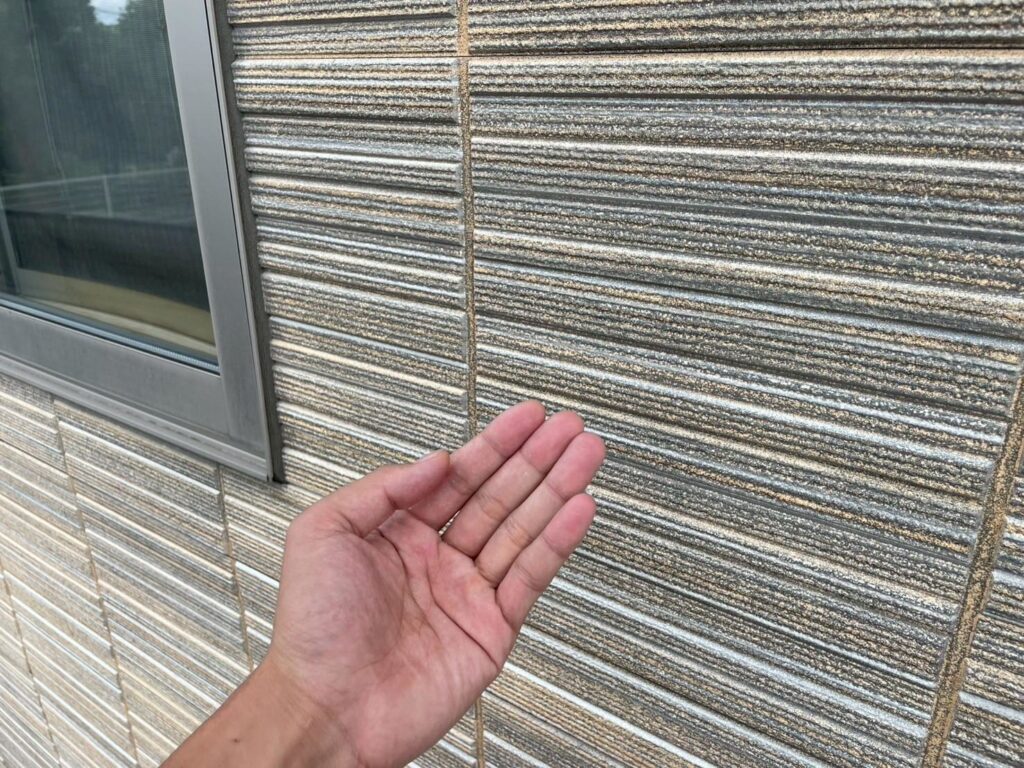 外壁を手でこすって確認。粉化（チョーキング）は大きく出ていませんが、面によって濃色部の退色が目立ちました。