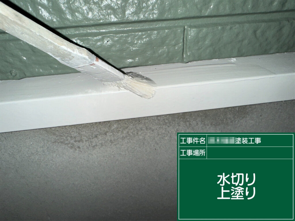 水切りの上塗りで最終仕上げです。端部まで丁寧に塗り込み、雨水が当たりやすい足元を美観・耐久性ともにしっかり保護します。