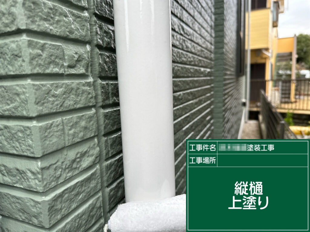 縦樋の上塗り工程です。N-90（白）で清潔感のある印象に整えつつ、塗膜で樋を保護し美観と耐候性を確保します。