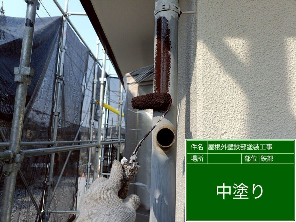 竪樋の丸い形状に沿って中塗りし、接続部や固定金具の周囲まで丁寧に塗り込みます。